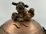 a small bronze statue of a dog on top of a bowl