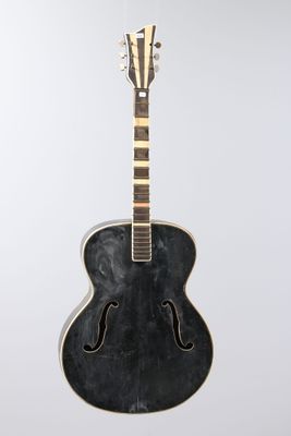 a black acoustic guitar sitting on top of a white surface