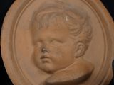 a clay picture of a baby on a plate next to a teddy bear