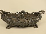 an antique bronze bowl with flowers and leaves on it