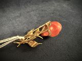 an image of a gold and coral colored broochle with a rope