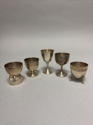 six silver goblets and cups on a white surface