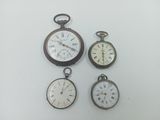 four different types of pocket watches are displayed on a white surface