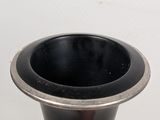 a black vase sitting on a table with a white background