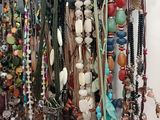 many different necklaces hanging on a hook on the wall