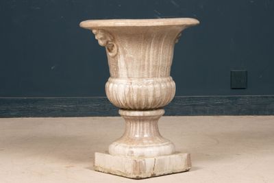 a stone vase sitting on the floor in front of a blue wall