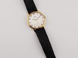 a gold plated wrist watch with black leather strap