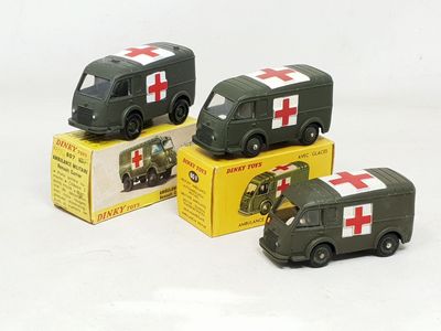 Trois véhicules militaires miniatures sont posés dans une boîte sur une surface blanche