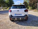 the rear end of a white citrole parked on a dirt road