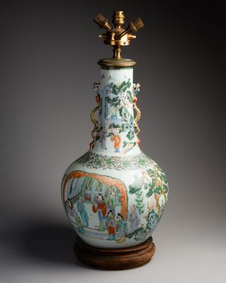 a vase on a wooden stand with a lamp on top