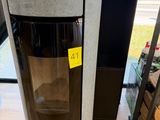 une poubelle noire et argentée sur laquelle est collé un autocollant jaune