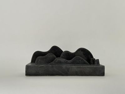 sculpture noire représentant une paire de chaussures posée sur une surface blanche