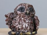 une petite figurine de chouette posée sur une table en bois