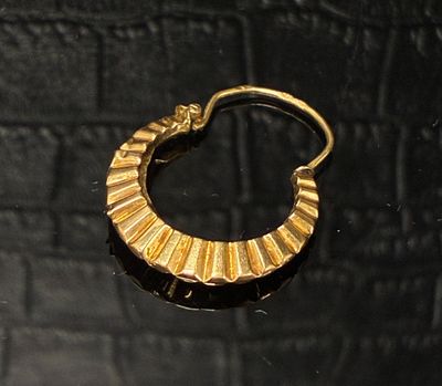 une image d'une paire de boucles d'oreilles en or sur une surface noire