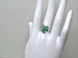 une image représentant la main d'une femme à laquelle est passée une bague verte