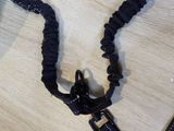 a black leash on a table next to a cell phone