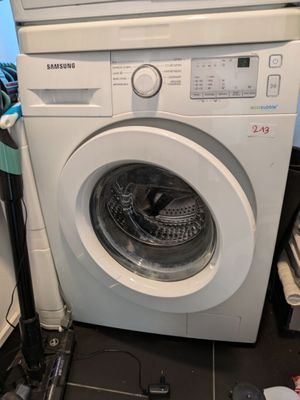 une machine à laver qui se trouve dans le coin d'une pièce