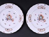two white plates with colorful designs on them sitting on a black surface