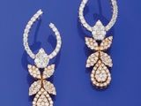 deux paires de boucles d'oreilles en diamant et en or posées sur un fond bleu