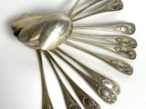 une cuillère en argent et un repose-cuillère posés sur une surface blanche