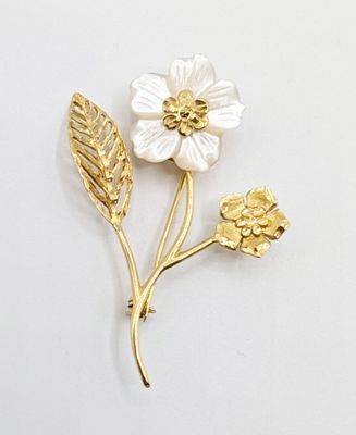 broche en or et blanche représentant une fleur et des feuilles sur fond blanc