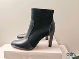 black leather ankle boots on top of a box on a white surface