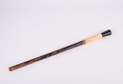 an old wooden stick with a black handle on a white surface