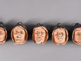 six ceramic heads of a man and a woman on a gray surface
