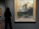woman standing in front of a painting in a museum looking at it