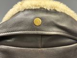 the back of a black leather jacket with a gold button