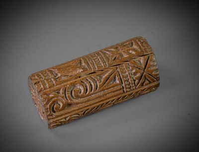 une vieille boîte sculptée, dont la surface grise est ornée de motifs sculptés
