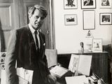 photographie en noir et blanc d'un homme en costume debout dans un bureau