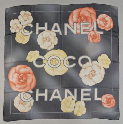 a chanel scarf with flowers on it hanging on a wall