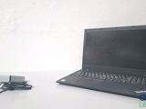 un ordinateur portable posé sur une table et auquel est relié un chargeur