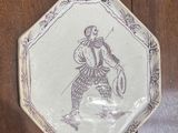 a white plate with a drawing on it hanging on a wooden wall