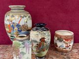 trois vases posés sur une table, avec un mur rouge en arrière-plan