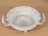 a white bowl with handles on a wooden table