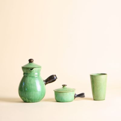 une théière verte et deux tasses placées l'une à côté de l'autre