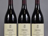 trois bouteilles de vin rouge posées sur une table