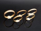 three gold rings with pearls on a black surface