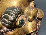 a gold mask with a green face on a black surface