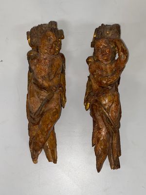 deux statues en bois représentant un garçon et une fille, posées sur une surface blanche
