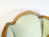 une chaise verte aux bordures dorées, avec un mur blanc en arrière-plan