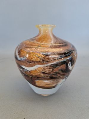 a glass vase that has a brown and white swirl on it