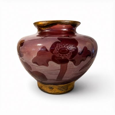 un vase rouge orné d'une fleur, posé sur une surface blanche