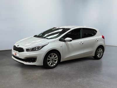 Une voiture blanche est garée dans une pièce aux murs blancs.