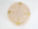 a pink plate with gold flowers on it on a white surface