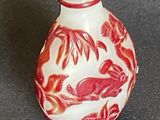a small red and white vase with a bird on it