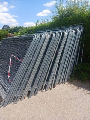 un tas de grillage métallique appuyé contre une clôture