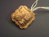 a gold heart shaped brooch on a white string